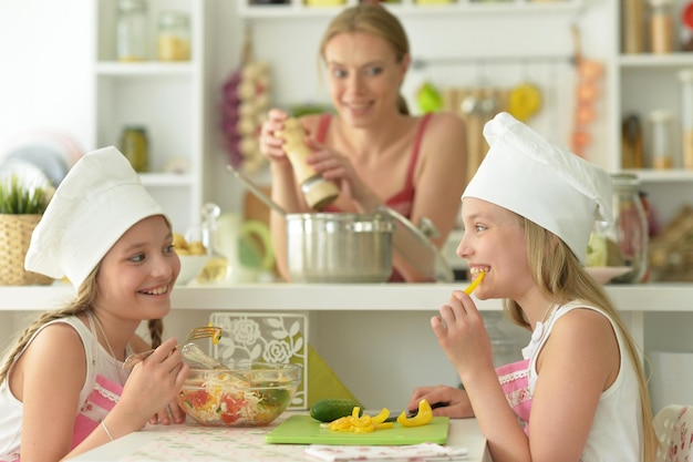 Nette glückliche Mädchen, die in der Küche kochen