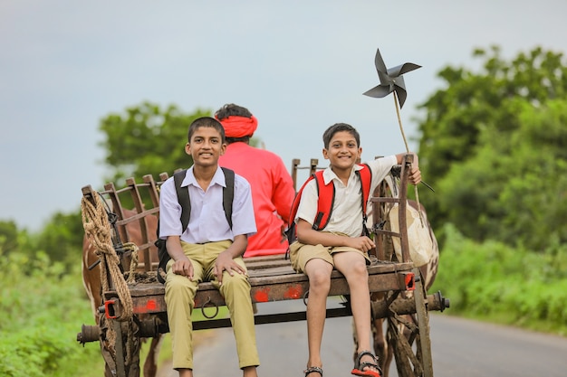 Nette indische Schüler in einem Ochsenkarren