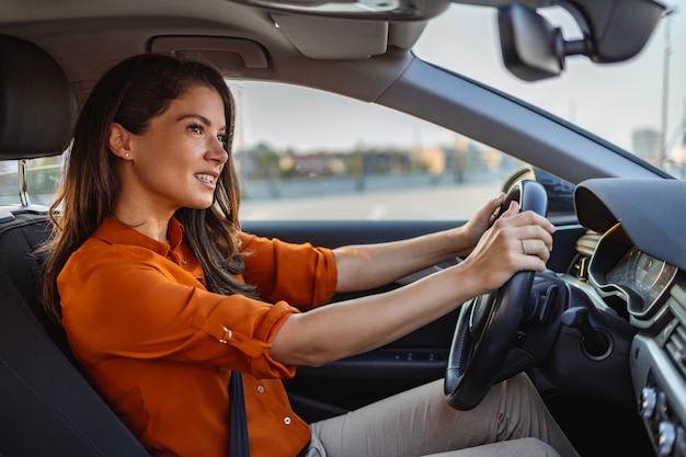 Nette junge Dame, die gerne Auto fährt Bild der schönen jungen Frau, die ein Auto fährt und lächelt Portrait eines glücklichen weiblichen Fahrers, der Auto mit Sicherheitsgurt steuert