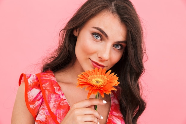 Nette junge Dame, die isolierte Wandhalteblume aufwirft.