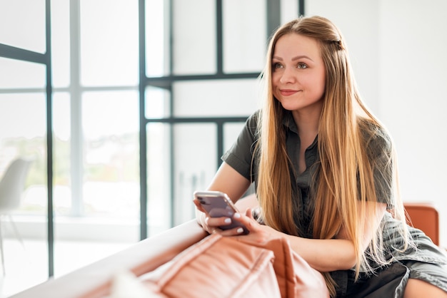 Nette junge Frau, die auf der Couch sitzt