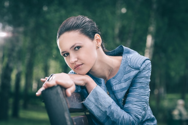 Nette junge Frau, die auf einer Parkbank sitzt