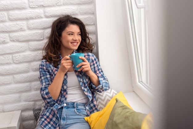 Nette junge Frau, die Morgenkaffee trinkt