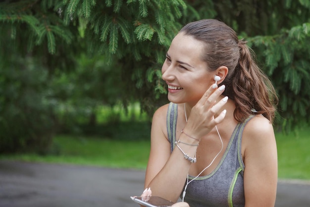 Foto nette junge frau, die musik beim joggen auf dem weg in einem grünen park hört