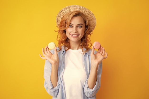 Nette junge Frau halten Makronen Diät-Diät-Konzept Schönes lächelndes junges Mädchen, das bunte Makronen über gelbem Hintergrund isst