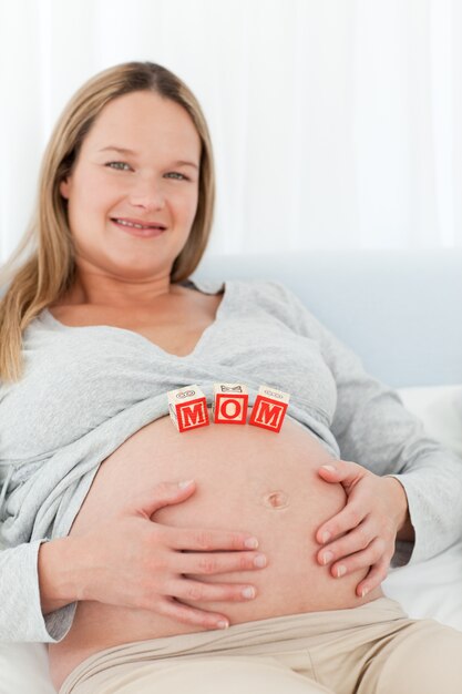 Nette junge Frau mit Mutterbuchstaben auf ihrem Bauch