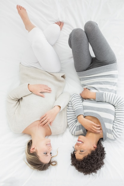 Nette junge Freundinnen, die im Bett liegen