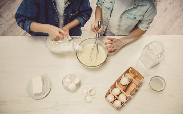 Nette Kinder, die Teig beim Backen in der Küche zubereiten.