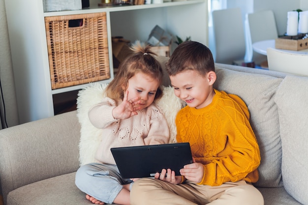 Nette Kinder sprechen per Videoanruf mit einem Tablet. Quarantäne. Eine Familie. Zuhause. Gemütlich.