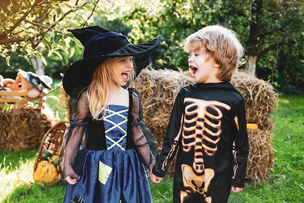 Nette Kindertochter und -sohn, die lustige Gesichter mit einem Kürbis machen Halloween-Kinder, die in genießen