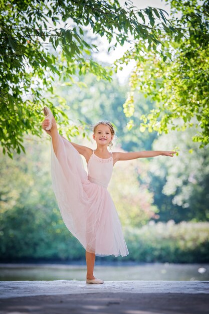 Nette kleine Ballerina in einem rosa Kleid im Sommer im Freien