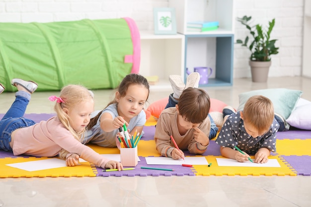 Nette kleine Kinder, die im Kindergarten zeichnen