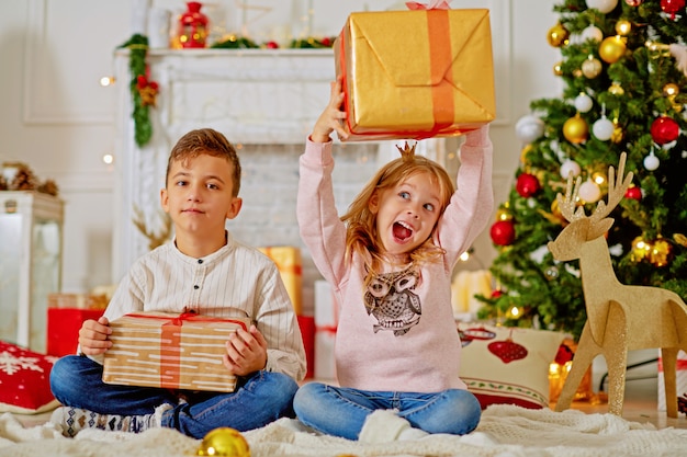 Nette kleine Kinder mit Weihnachtsgeschenken zu Hause