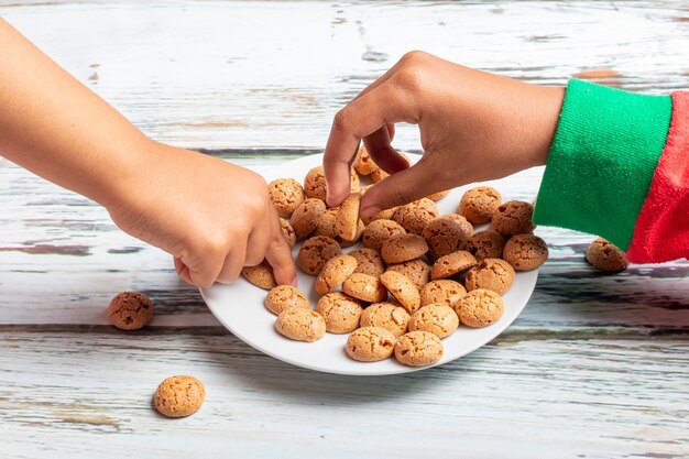 Nette kleine Mädchen spielt mit Sankt Plätzchen und Milch am Weihnachten