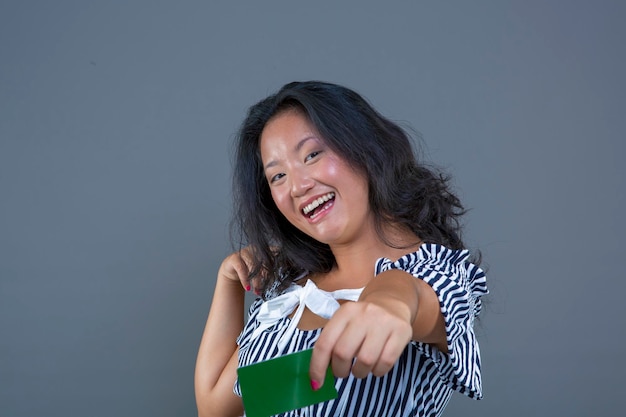Nette lächelnde asiatische Frau, die Chroma-Karte in ihrer Hand zeigt