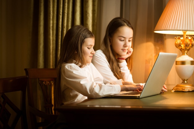 Nette Mädchen, die am Tisch sitzen und Laptop benutzen