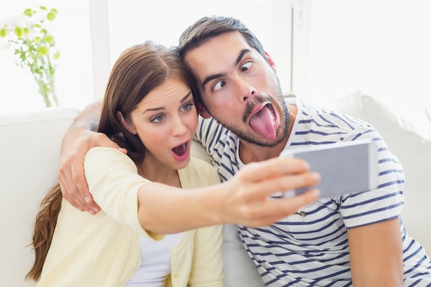 Nette Paare, die ein selfie auf Couch nehmen