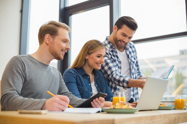 Nette positive kluge Leute, die zusammen sitzen und ihr Projekt diskutieren, während sie im Team arbeiten