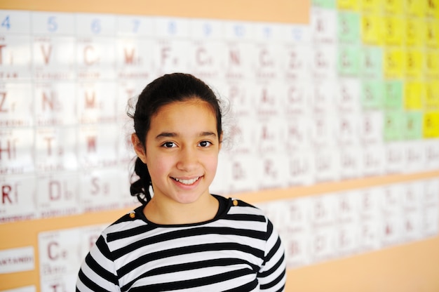 Nette reizende Schulkinder an der Klasse mit Periodensystem der Elemente