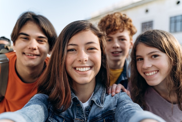 Nette, schöne Teenager, die Selfies machen. Freundliche Gruppenkinder machen Selfies im Freien