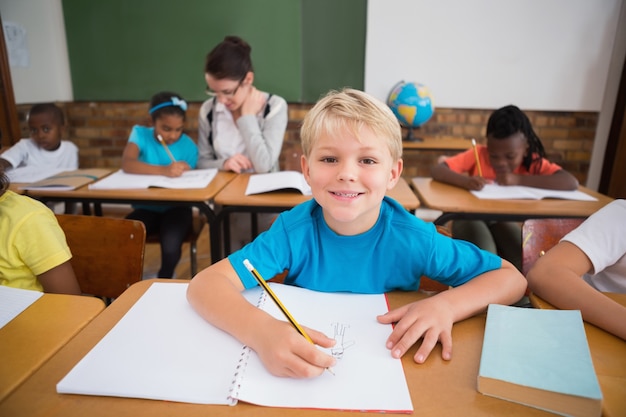 Nette Schüler, die am Schreibtisch im Klassenzimmer schreiben