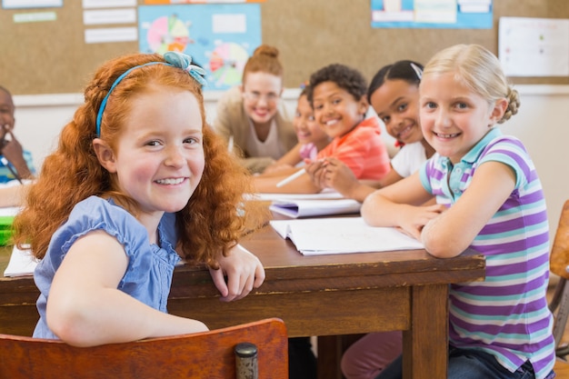 Foto nette schüler, die am schreibtisch in klassenzimmer schreiben