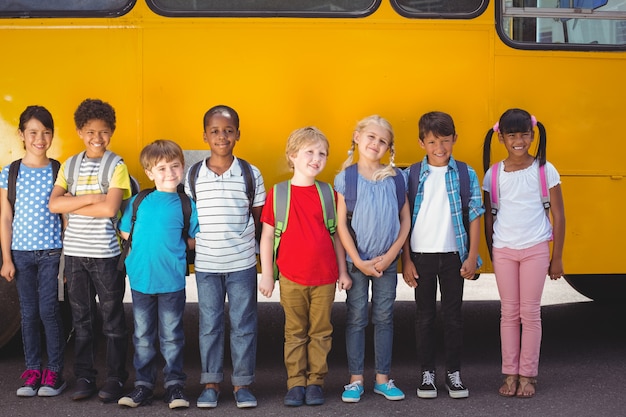 Nette schüler, die an der kamera durch den schulbus lächeln