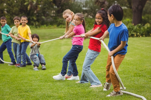 Nette Schüler, die draußen Tauziehen auf dem Gras spielen