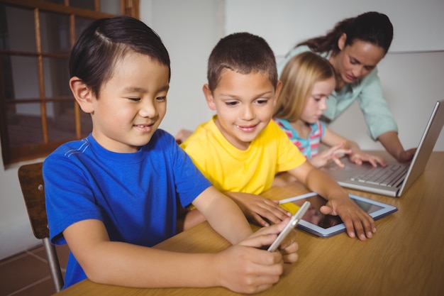 Nette Schüler in der Klasse unter Verwendung des Laptops und der Tablette