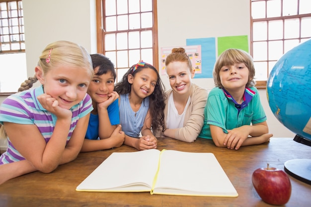 Nette Schüler und Lehrer, die an der Kamera im Klassenzimmer lächeln