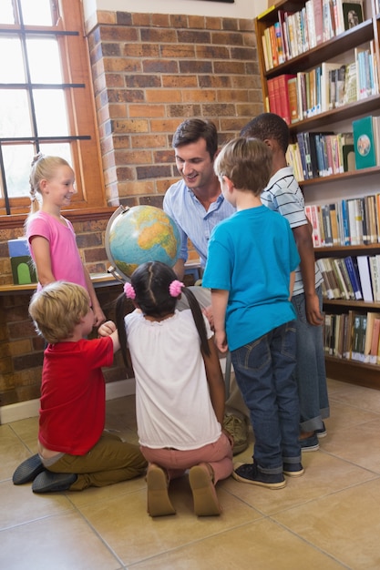 Nette Schüler und Lehrer, die Kugel in der Bibliothek betrachten