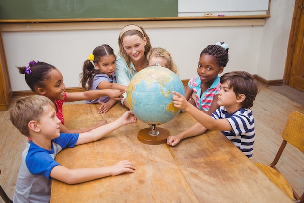 Nette Schüler und Lehrer im Klassenzimmer mit Kugel