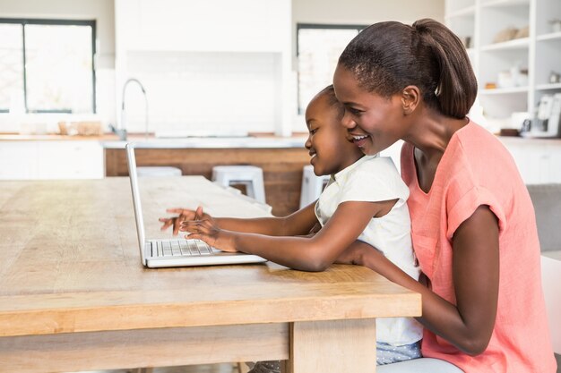 Nette Tochter, die Laptop am Schreibtisch mit Mutter verwendet