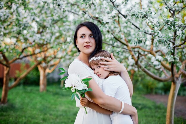 Nette Tochter und Mutter, die im blühenden Frühlingsgarten umarmen