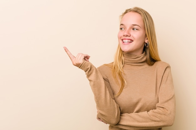 Nette und natürliche Jugendlichfrau, die mit dem Zeigefinger weg nett zeigen lächelt.