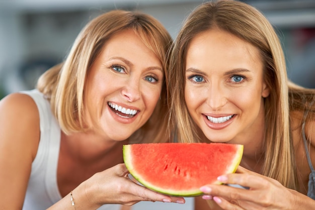 Nette zwei erwachsene Mädchen in der Küche mit Wassermelone