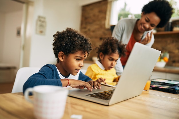 Netter afroamerikanischer Junge, der zu Hause Laptop verwendet