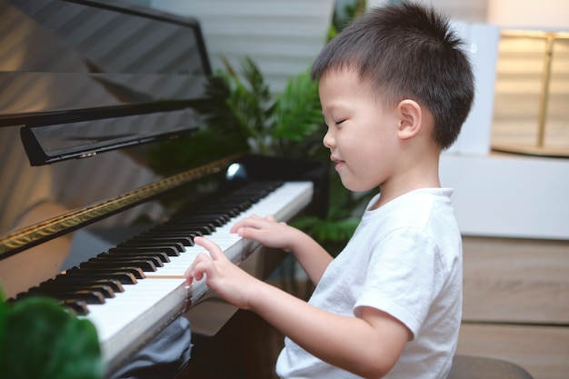 Netter asiatischer Junge, der das Klavier spielt