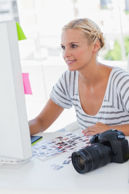 Netter Bildeditor, der an ihrem Schreibtisch arbeitet