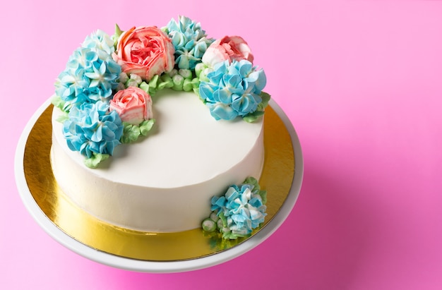 Netter Blumenkuchen auf Kuchenstand und hellrosa Hintergrund, Draufsicht