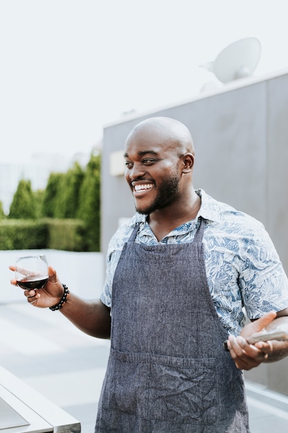 Netter Chef mit Grillzangen und einem Weinglas