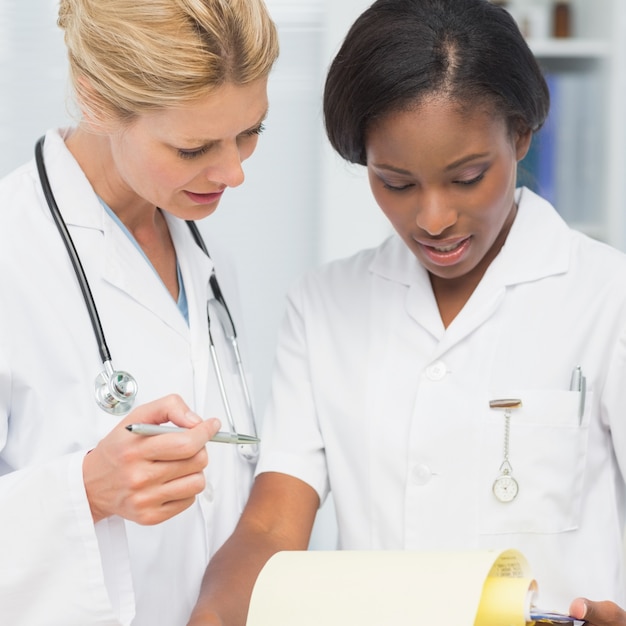 Netter Doktor und Krankenschwester, die zusammen Datei in einem Büro am Krankenhaus übergehen