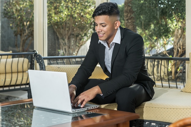 Netter ethnischer Unternehmergrasenlaptop