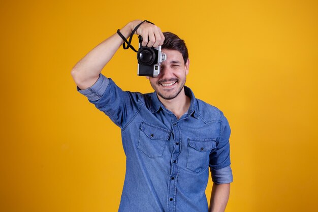 Netter Fotograf auf gelbem Hintergrund. Mann mit Fotokamera