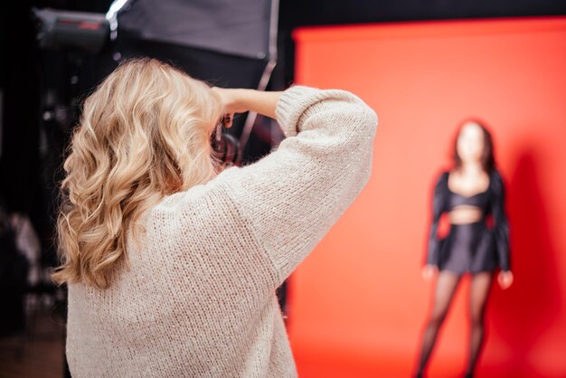 Netter Frauenfotograf, der Bilder von Modell im Fotostudio macht