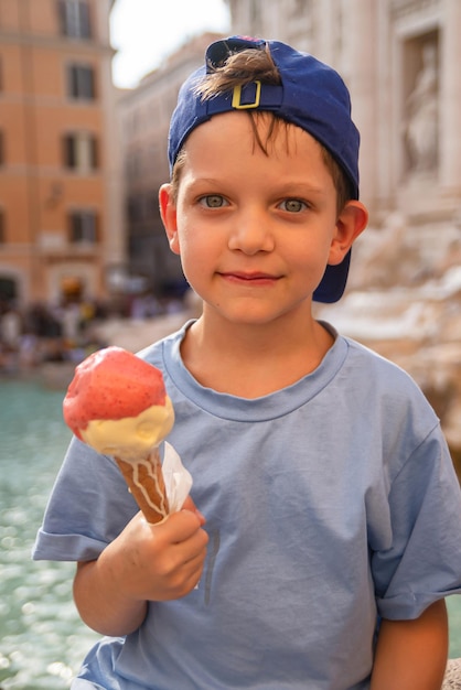 Netter fröhlicher Junge, 7 Jahre alt, isst Eisgelato in der Nähe des Trevi-Brunnens in Rom Italien