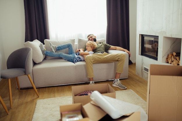 Netter glücklicher Junge, der mit Papa auf dem Sofa liegt