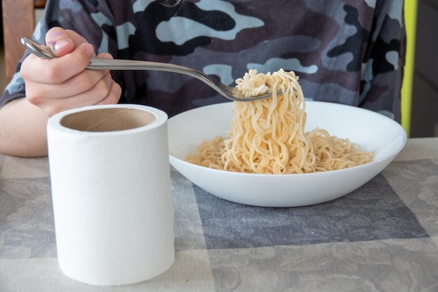 Foto netter glücklicher junge, der spaghetti in der küche isst