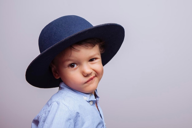 Netter glücklicher Junge in einem blauen Hut auf einem weißen Hintergrund lächelt das emotionale Kind horizontal
