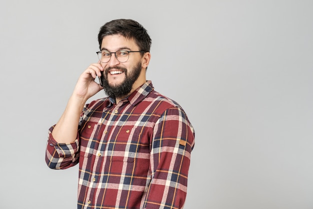 Netter glücklicher junger Mann, der die lächelnde Unterhaltung am Telefon lacht